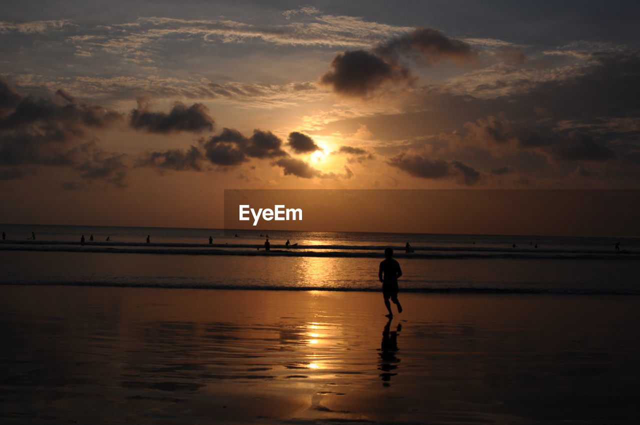 Silhouette man running at beach during sunset