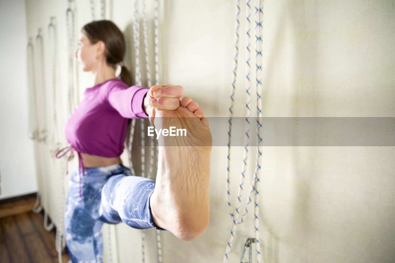 Side view of woman standing against wall at home