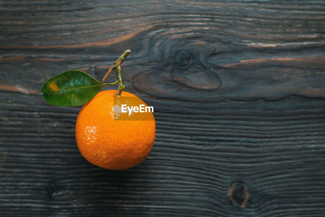 CLOSE-UP OF ORANGE FRUITS ON WOOD