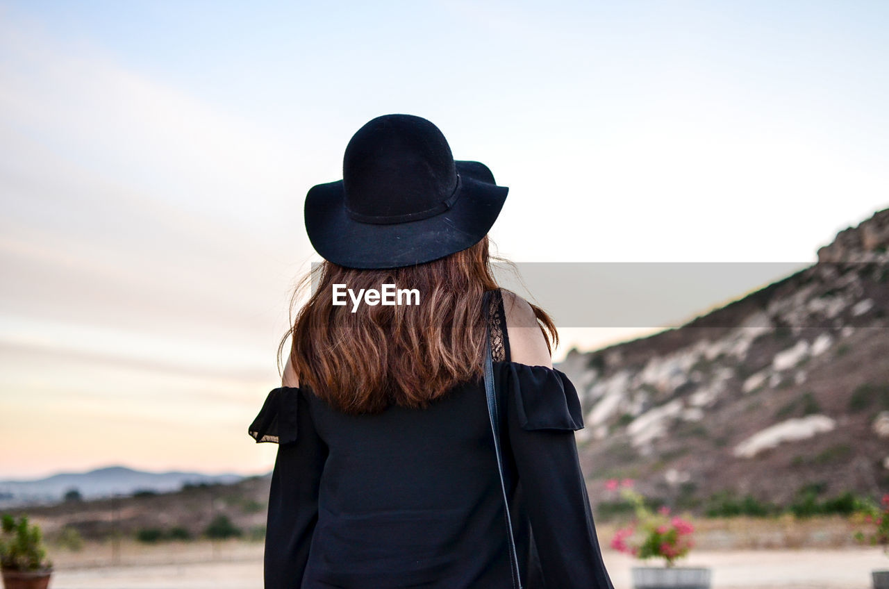 Rear view of woman wearing hat standing against sky