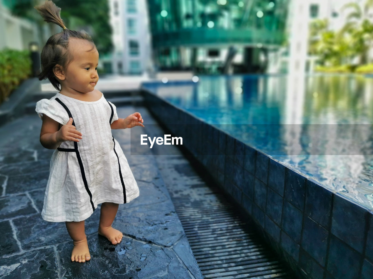 Full length of baby girl standing infront of swimming pool