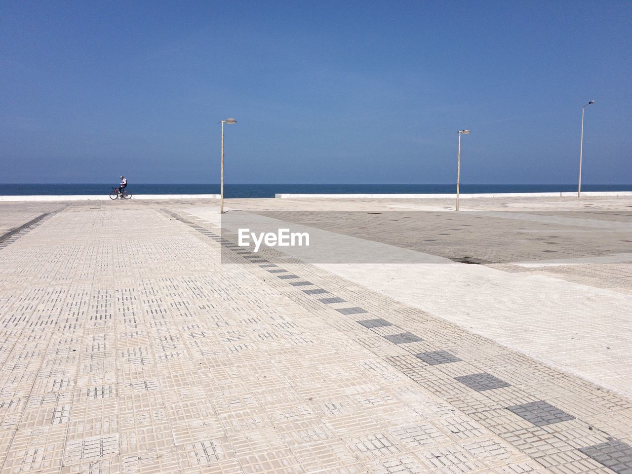 Scenic view towards the beach from an urban plaza against clear blue sky 