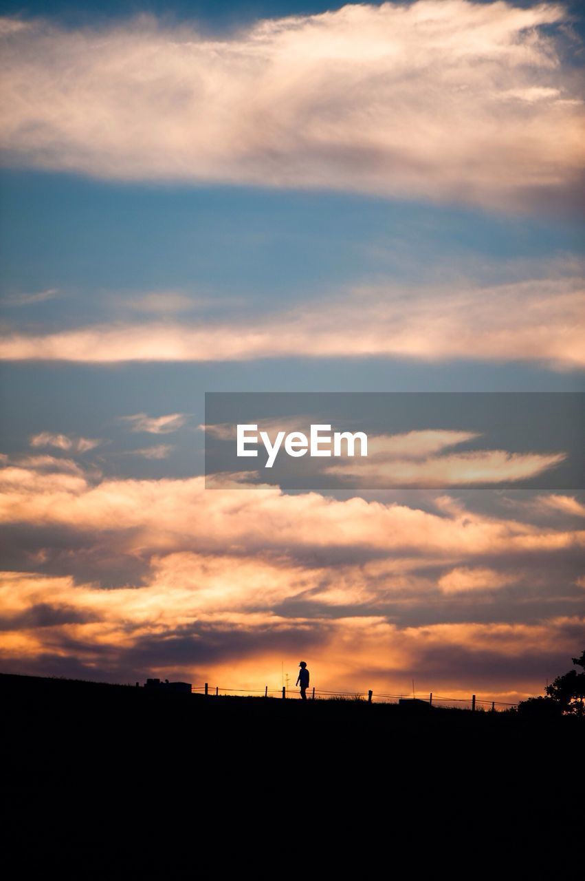 Low angle view of person walking at olympic park against cloudy sky during sunset