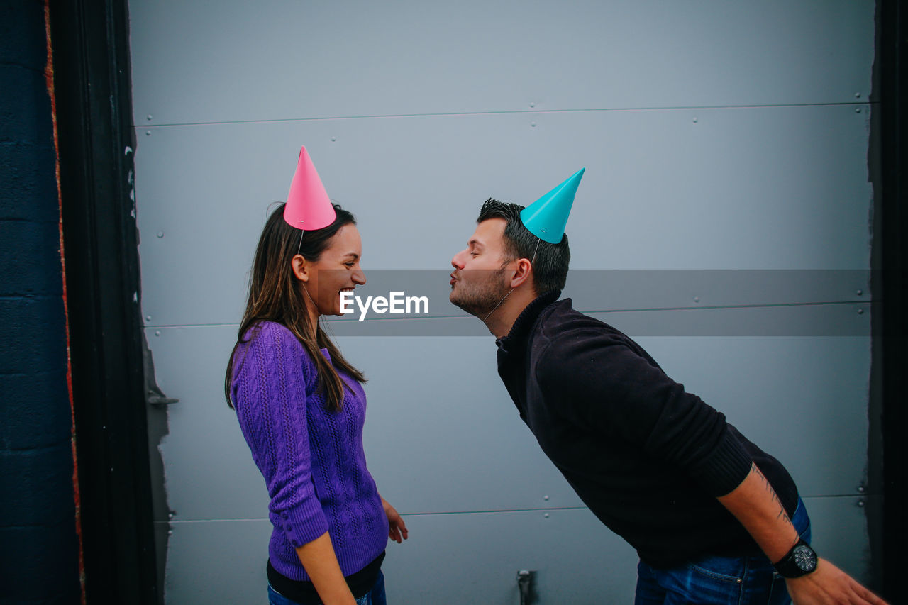 Side view of man blowing air by woman standing while smiling