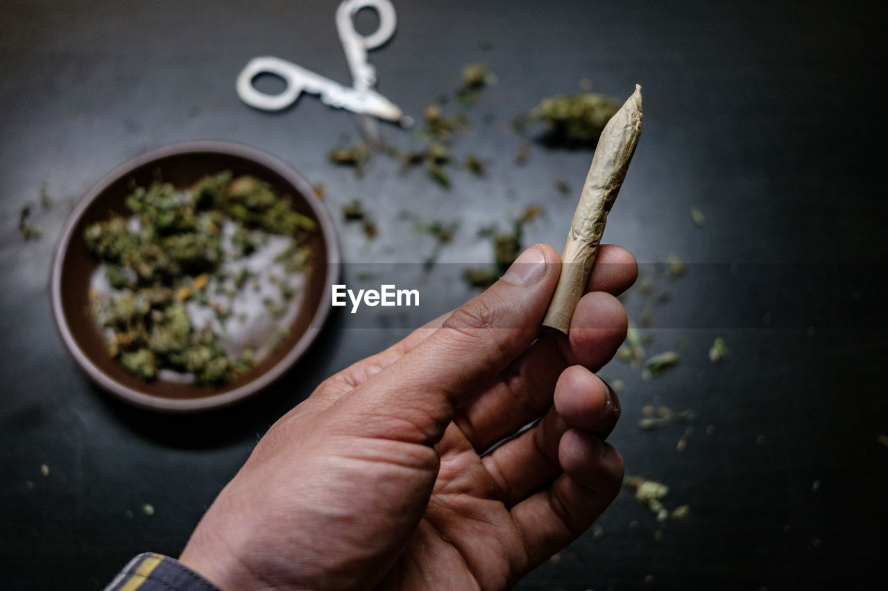 Cropped hands of man holding marijuana joint