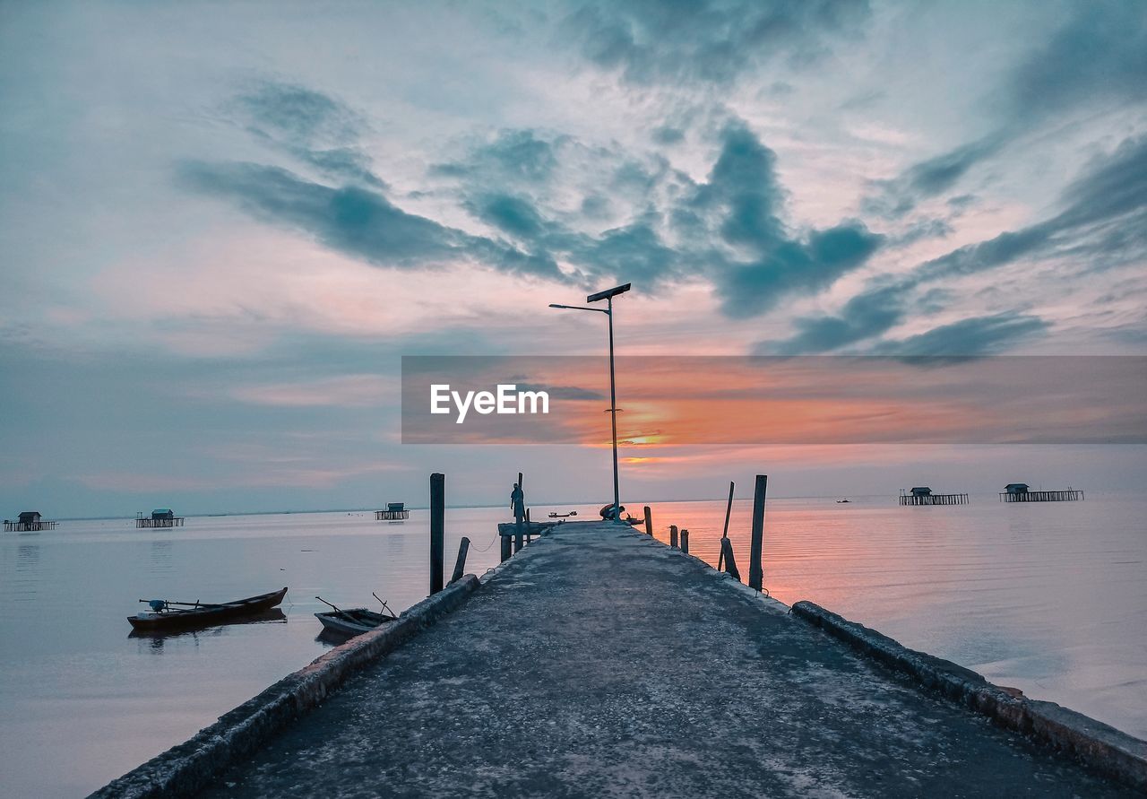 Pier over sea against sky during sunset