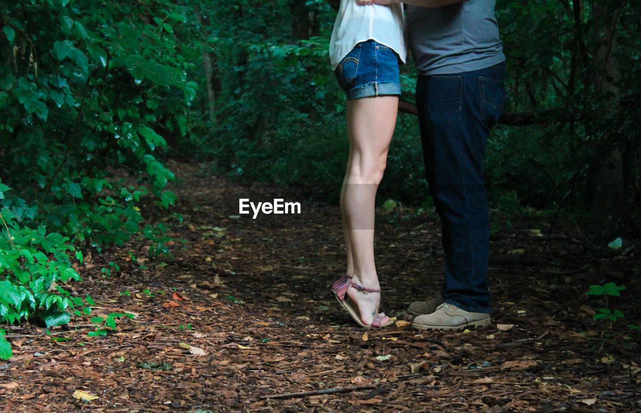 Low section of couple standing in forest