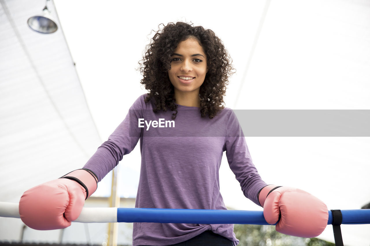 Portrait of smiling female boxer standing in boxing ring