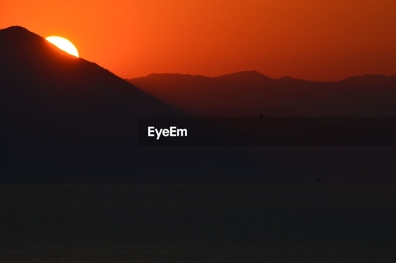 Scenic view of silhouette mountains against clear sky during sunset