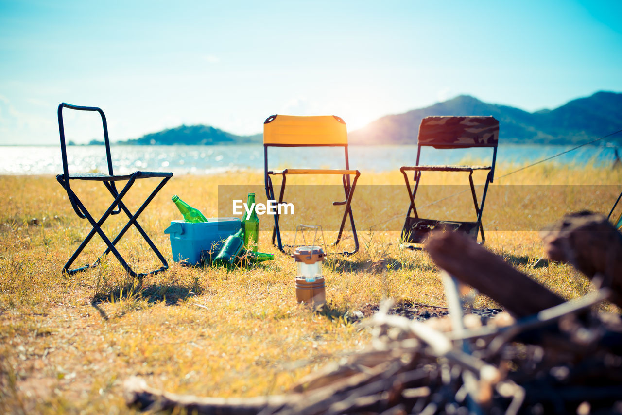 Empty chairs on field during sunny day