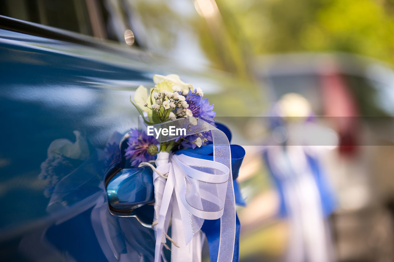 Close-up of flowers and ribbons on car door