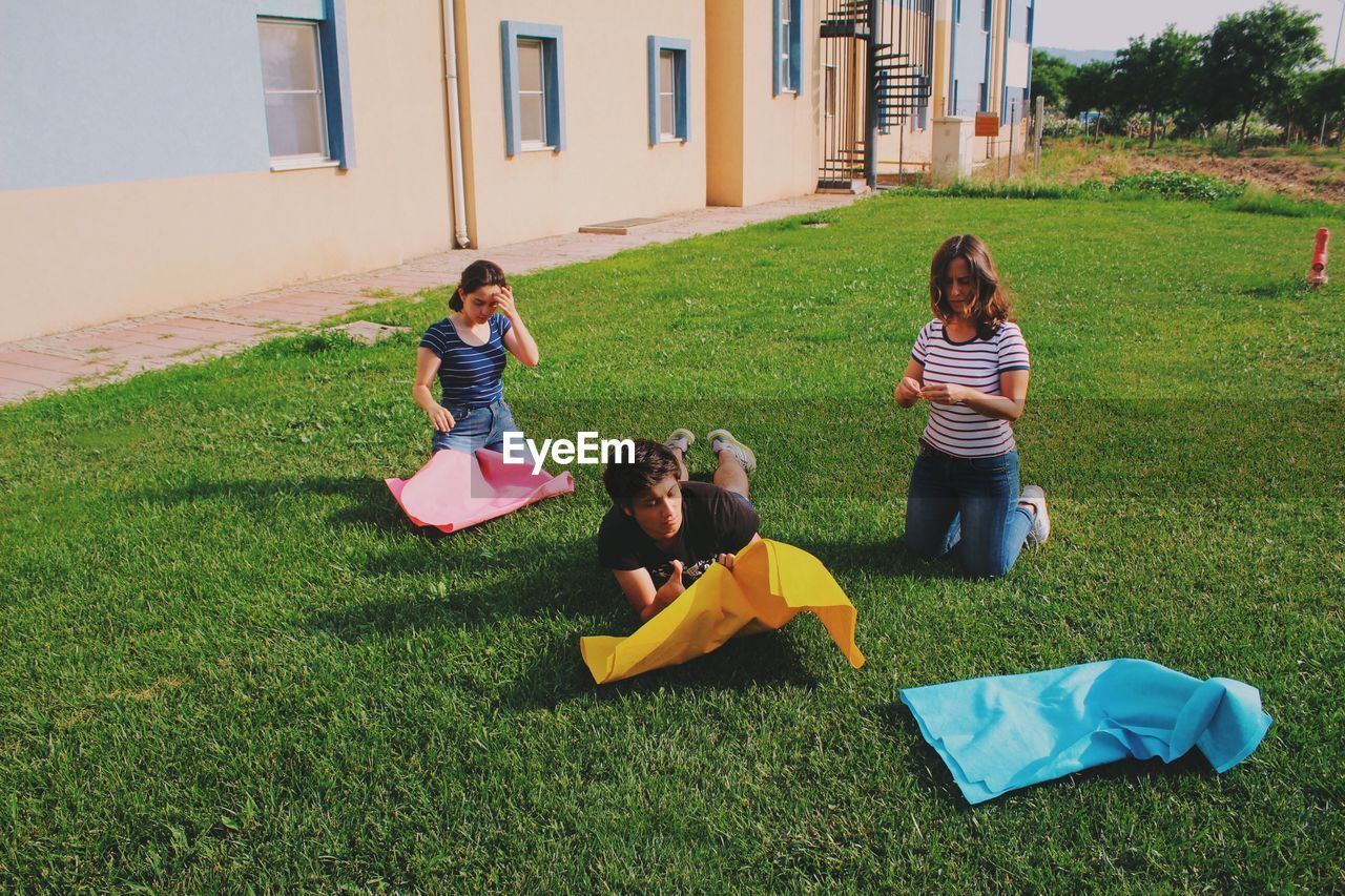 High angle view of friends with craft paper on grassy field