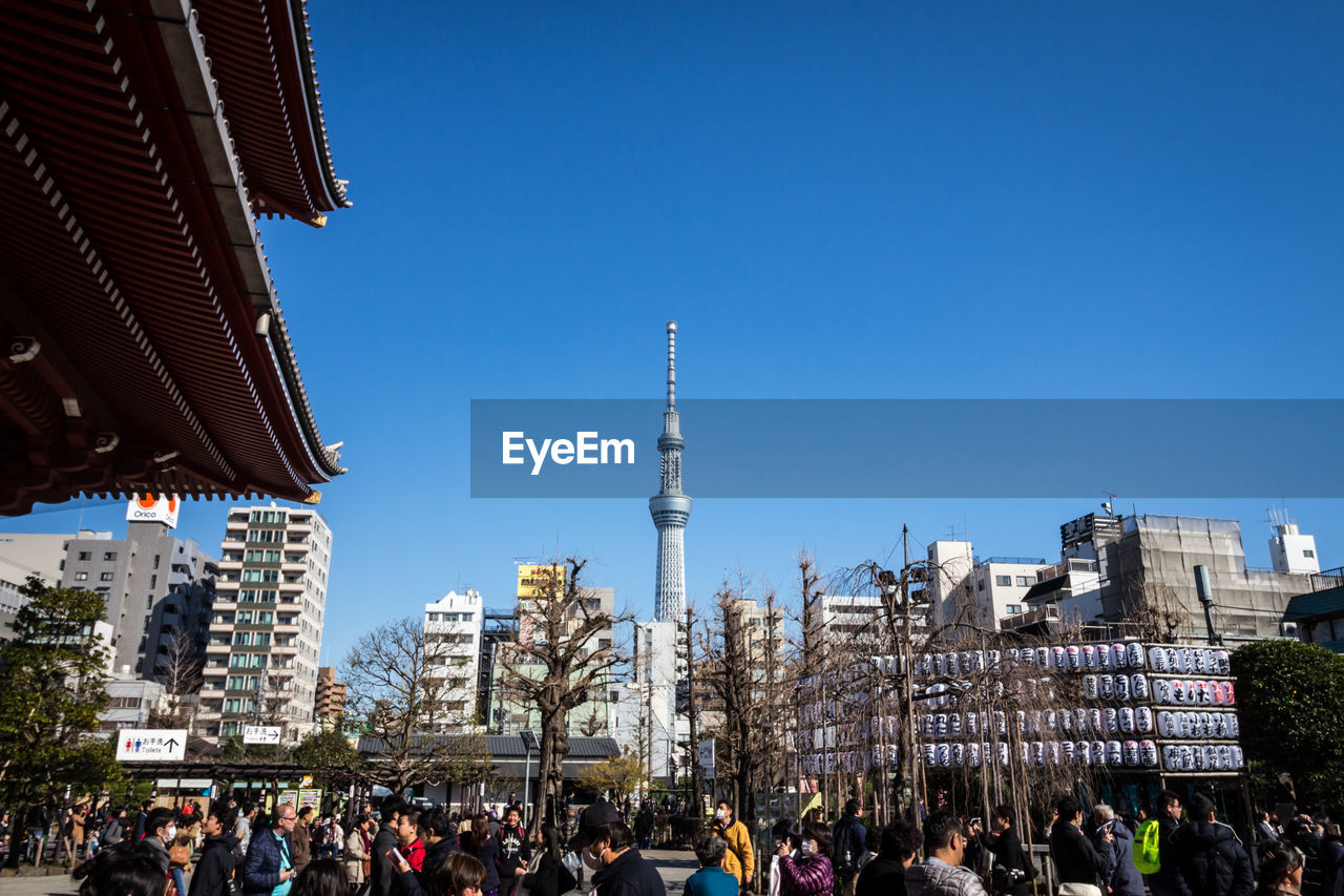 People standing by senso-ji against clear blue sky