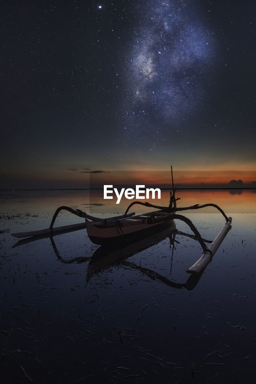 Boat in lake against sky at night