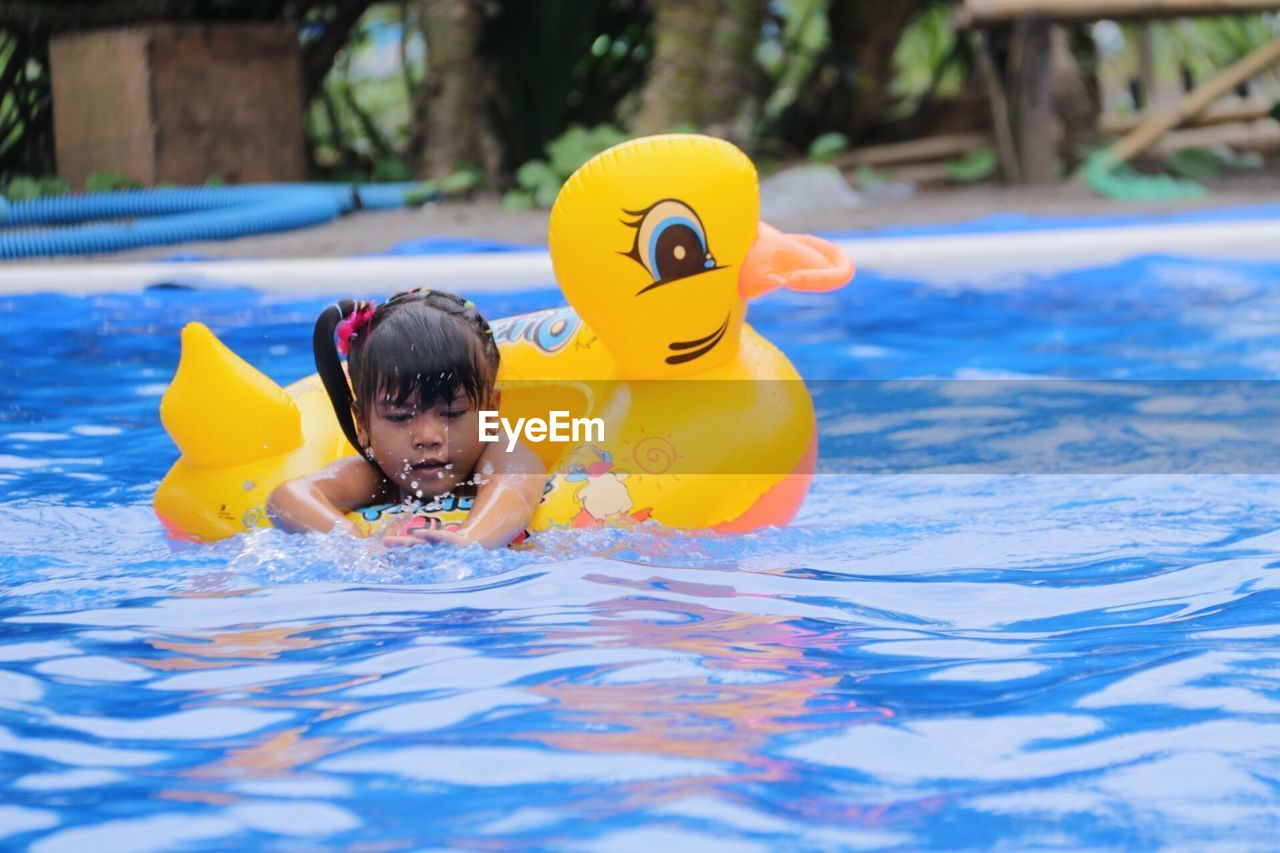 Girl with inflatable duck swimming in pool
