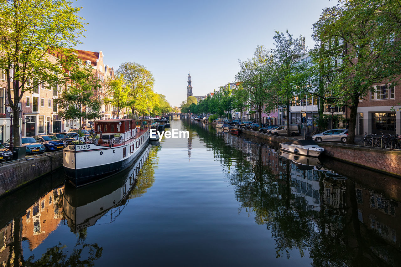 canal, water, body of water, architecture, waterway, reflection, nautical vessel, built structure, building exterior, city, transportation, nature, channel, tree, travel destinations, sky, building, mode of transportation, plant, travel, tourism, vehicle, town, cityscape, moored, boat, waterfront, outdoors, no people, residential district, clear sky, tranquility, day, watercraft, house, street, holiday, landscape, trip, vacation, bridge, ship, beauty in nature