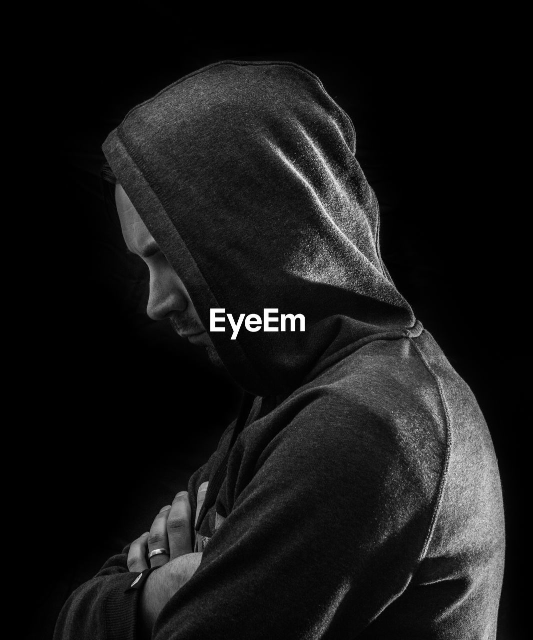 Side view of man wearing hood against black background