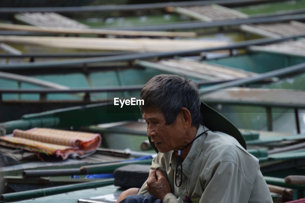 Senior man sitting against nautical vessels