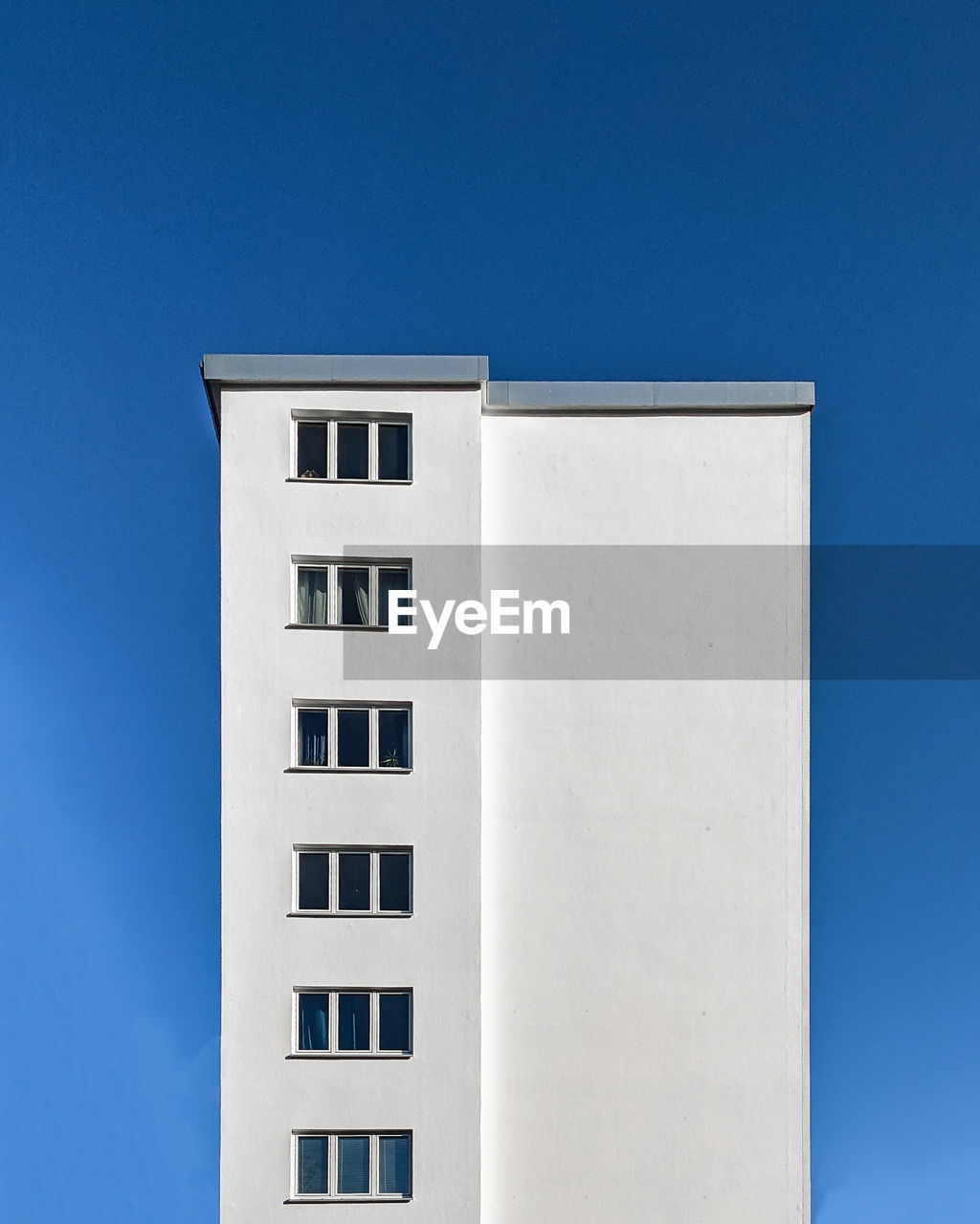 LOW ANGLE VIEW OF WHITE BUILDING AGAINST CLEAR BLUE SKY