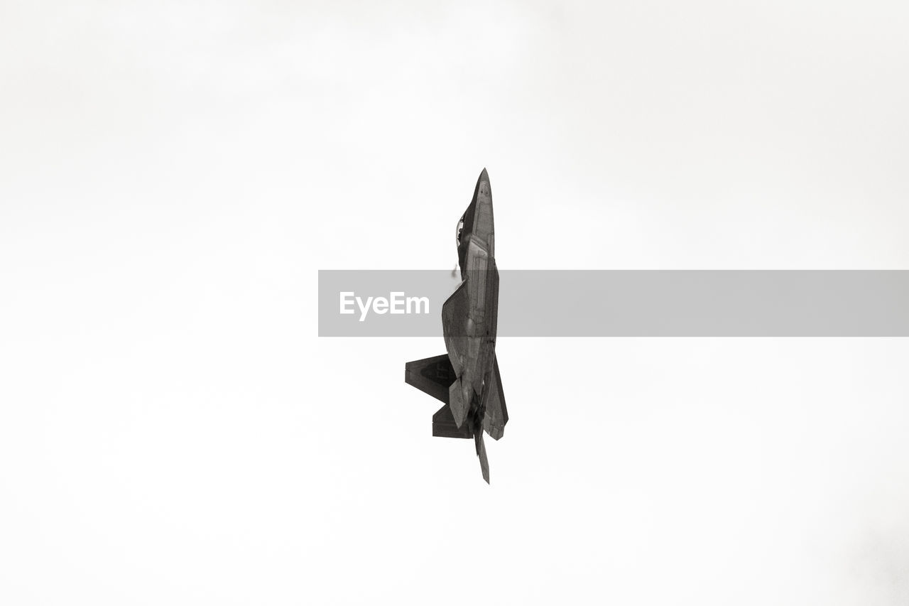 Low angle view of f-22 raptor flying against clear sky