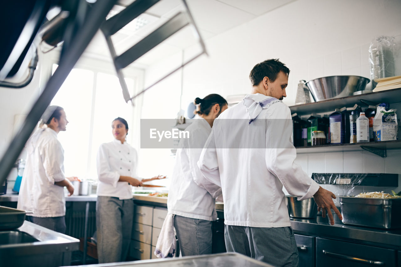 Chefs preparing food at counter in commercial kitchen