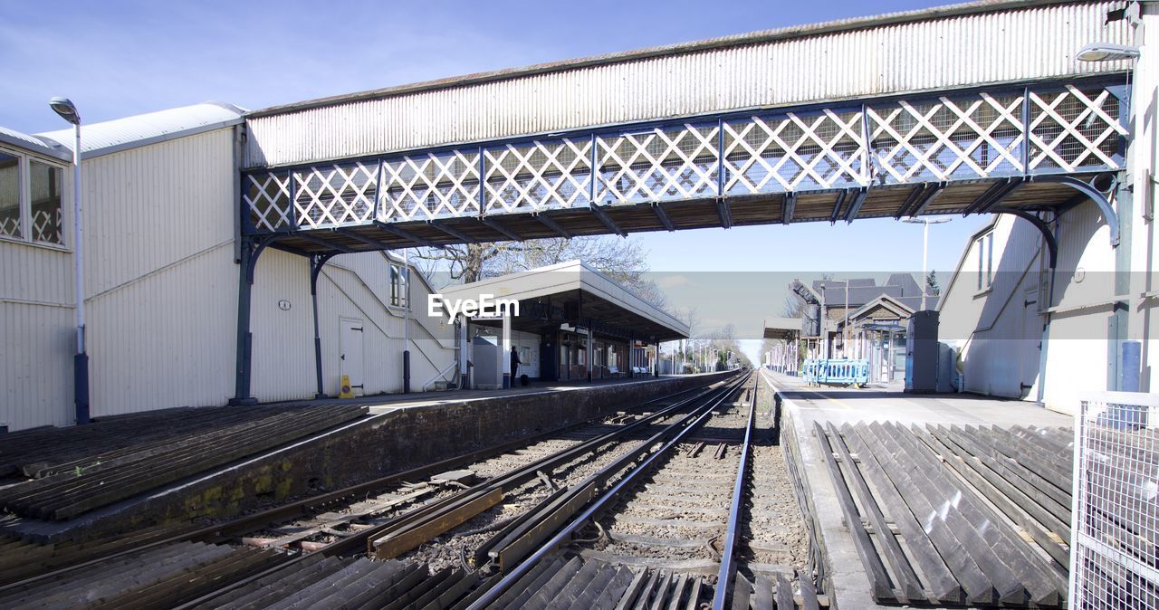 RAILROAD TRACKS BY BUILDING AGAINST SKY