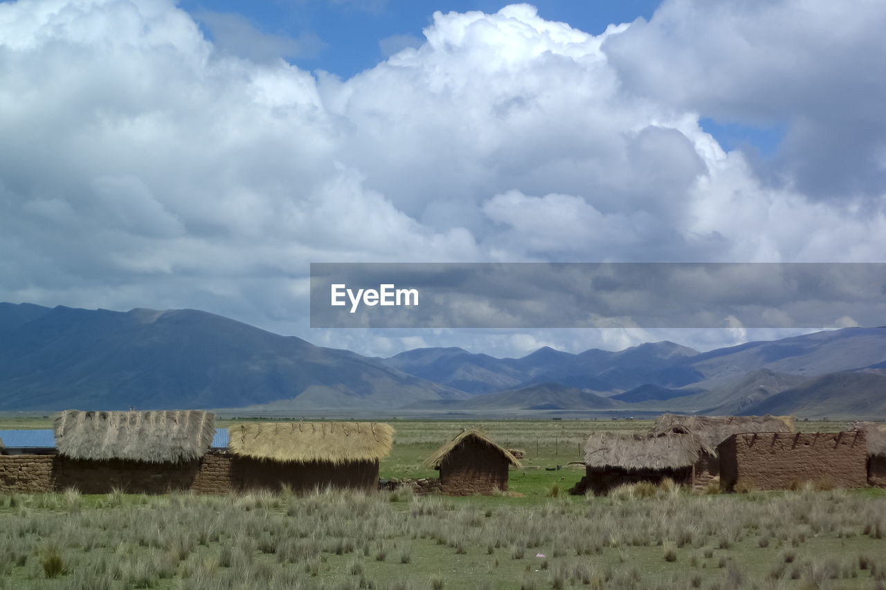 HAY BALES ON FIELD AGAINST MOUNTAINS