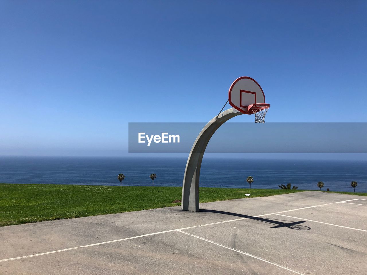 Basketball hoop by sea against clear sky