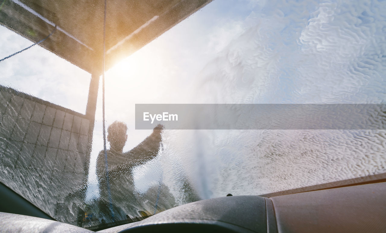 Man washing car seen through windshield