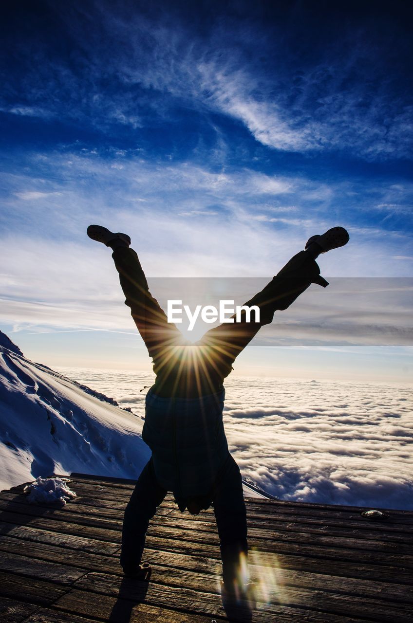 Silhouette man doing handstand at observation point during winter