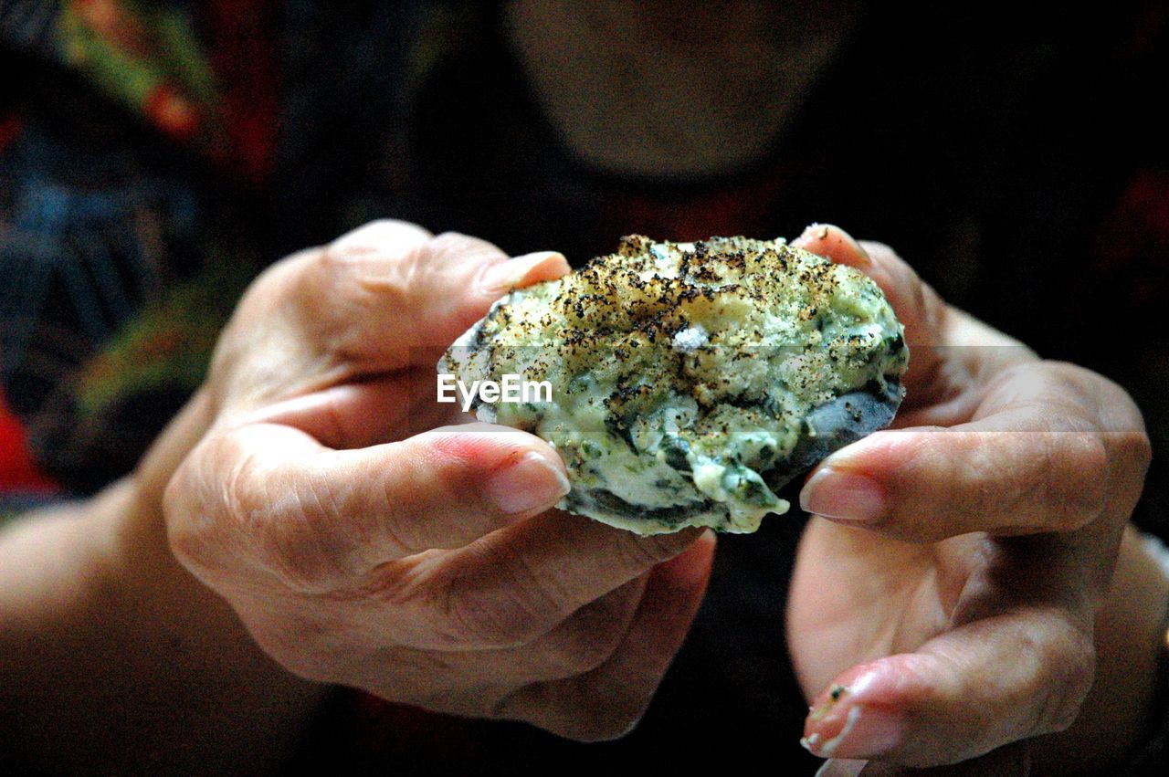 Close-up of person's hand  holding baked oyster