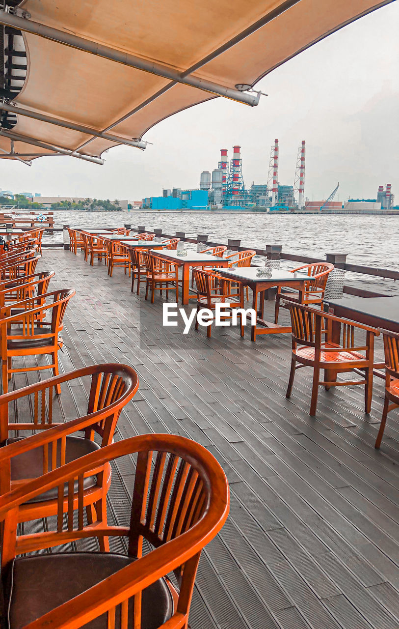 Empty chairs and tables against the sea view