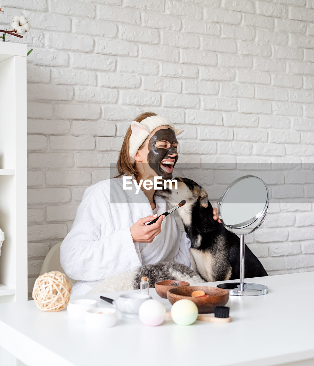 Self care. young caucasian woman wearing bathrobes doing spa procedures with her dog