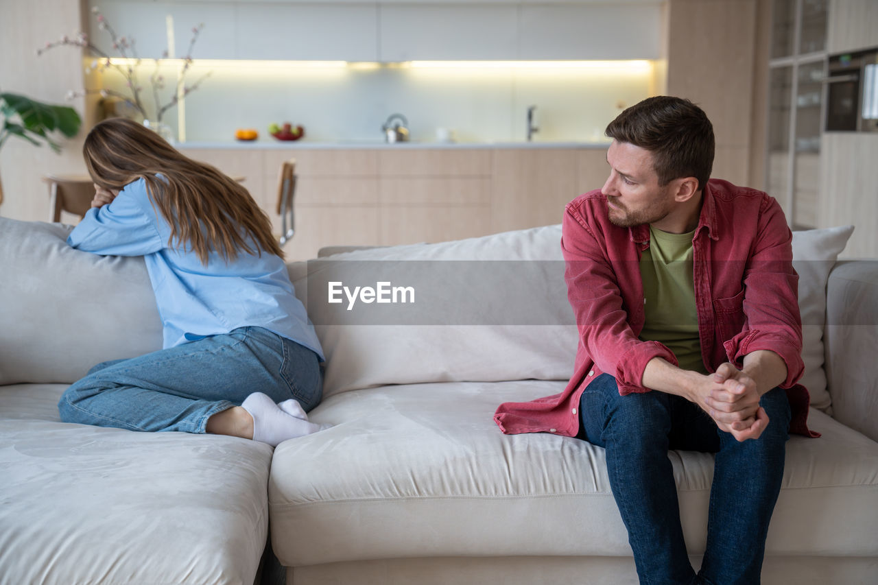 young woman using mobile phone while sitting on sofa at home