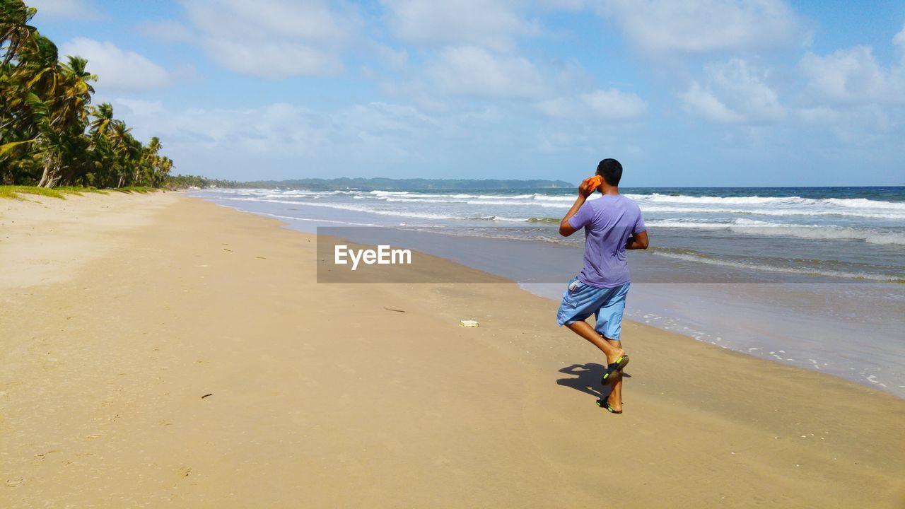 Man using smart phone while walking on beach