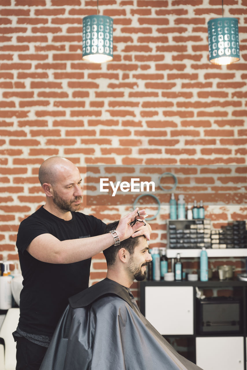 Barber cutting man hair in salon