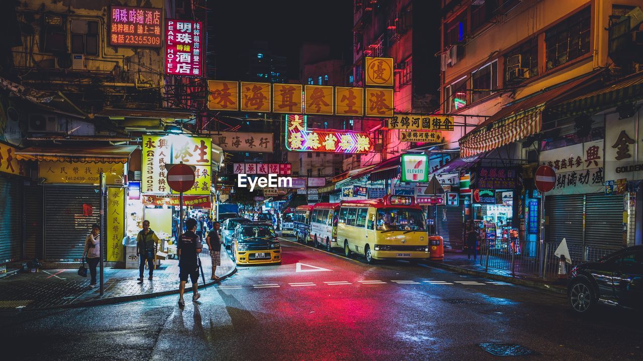 People on street by buildings at night