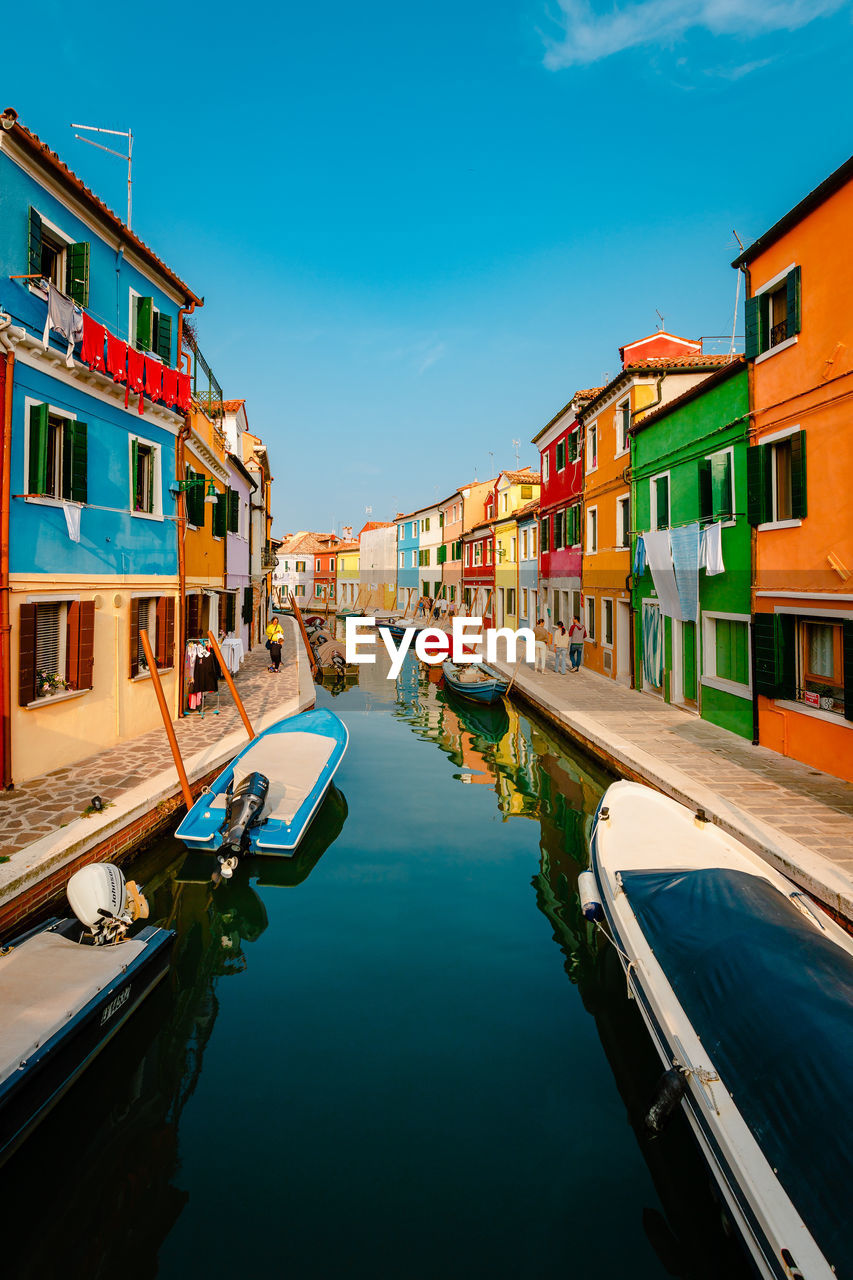Canal with boats and characteristic colorful houses of burano with tourists