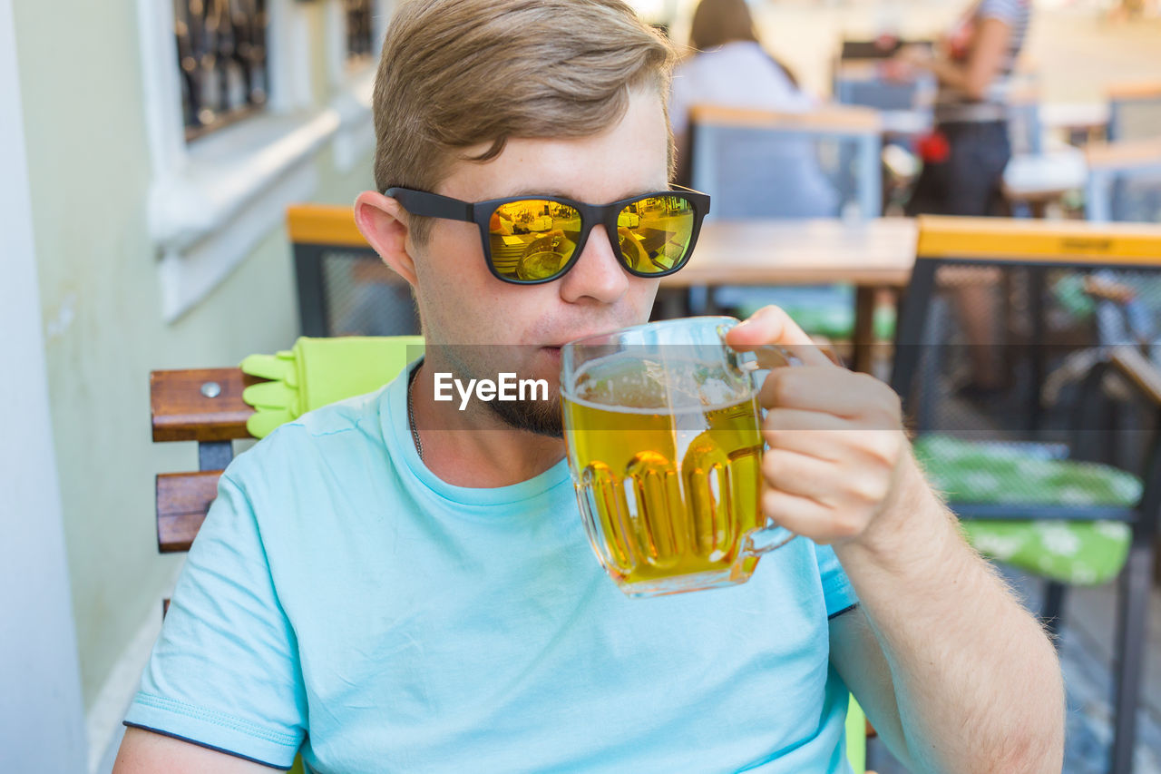 PORTRAIT OF YOUNG MAN DRINKING GLASS