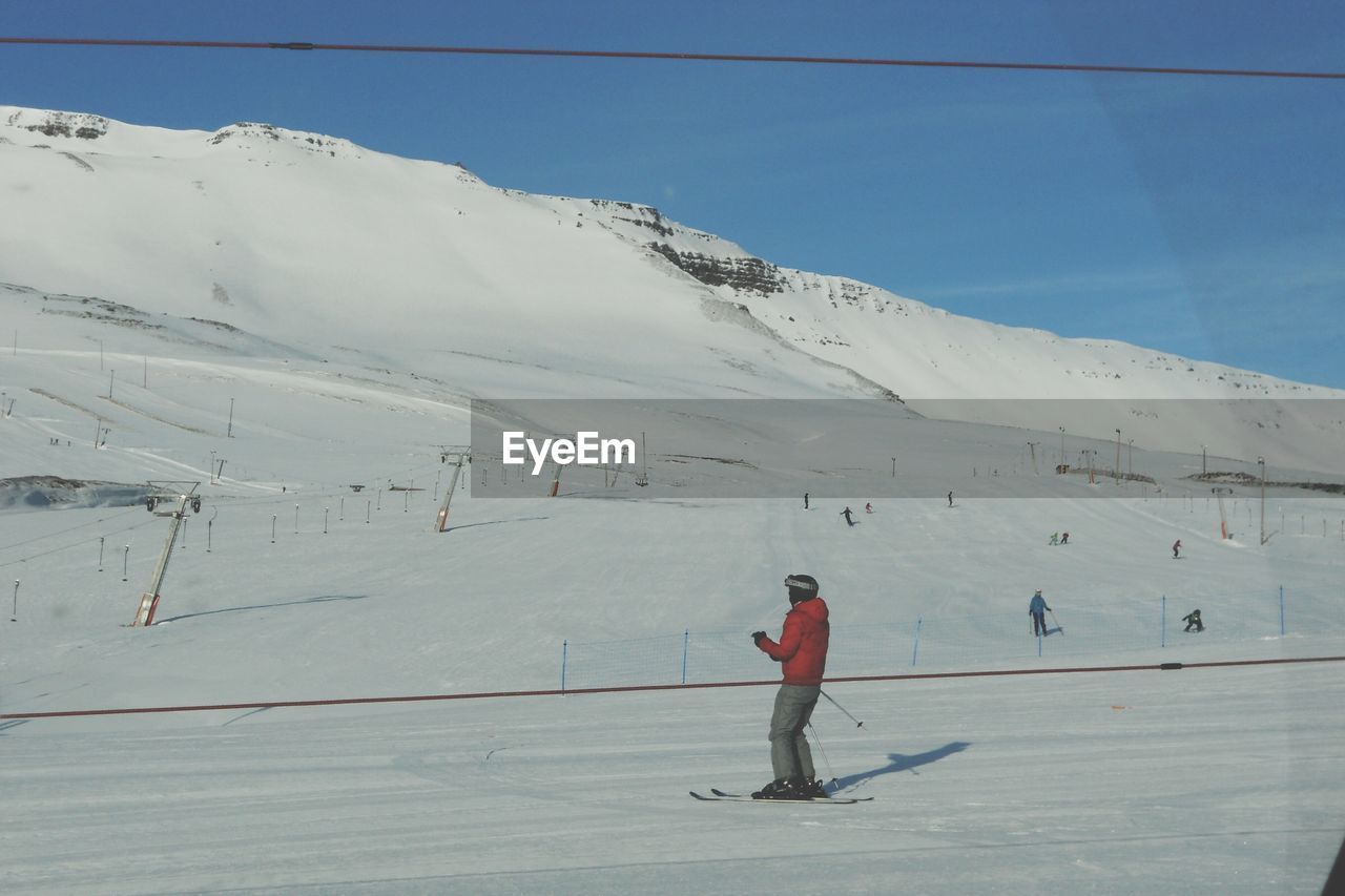 FULL LENGTH OF MAN SKIING ON SNOW COVERED LANDSCAPE