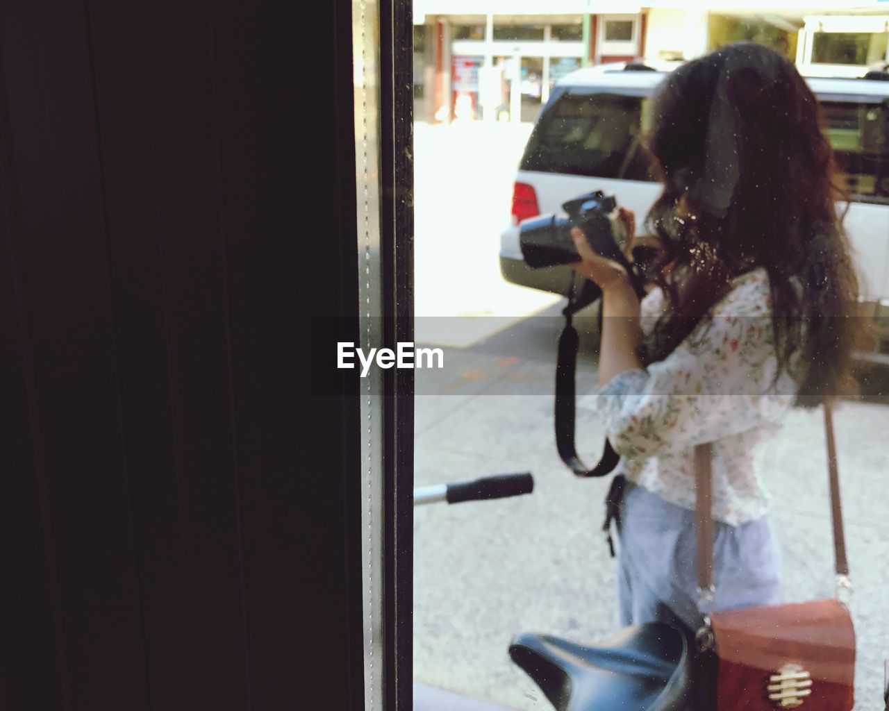 Woman photographing through camera in city