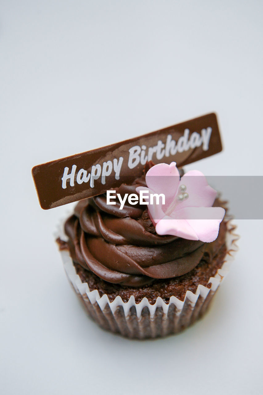 Close-up of cupcake with happy birthday message on white background