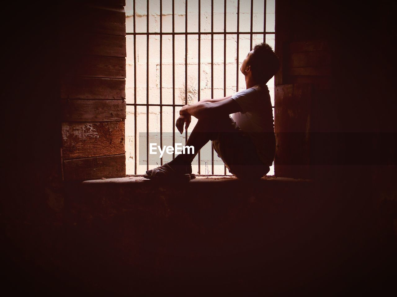 Side view of man sitting by window