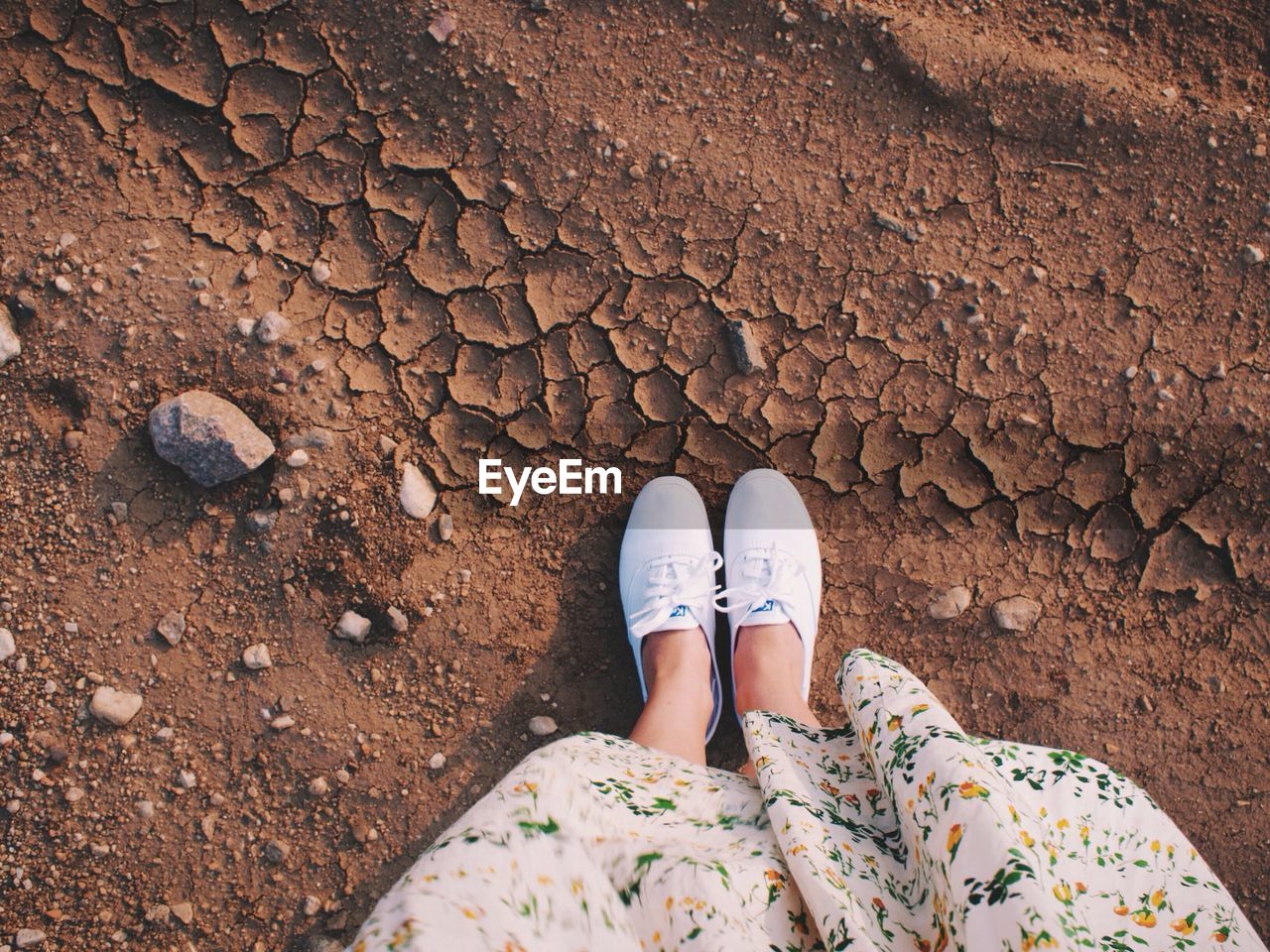 Low section of girl standing on cracked field