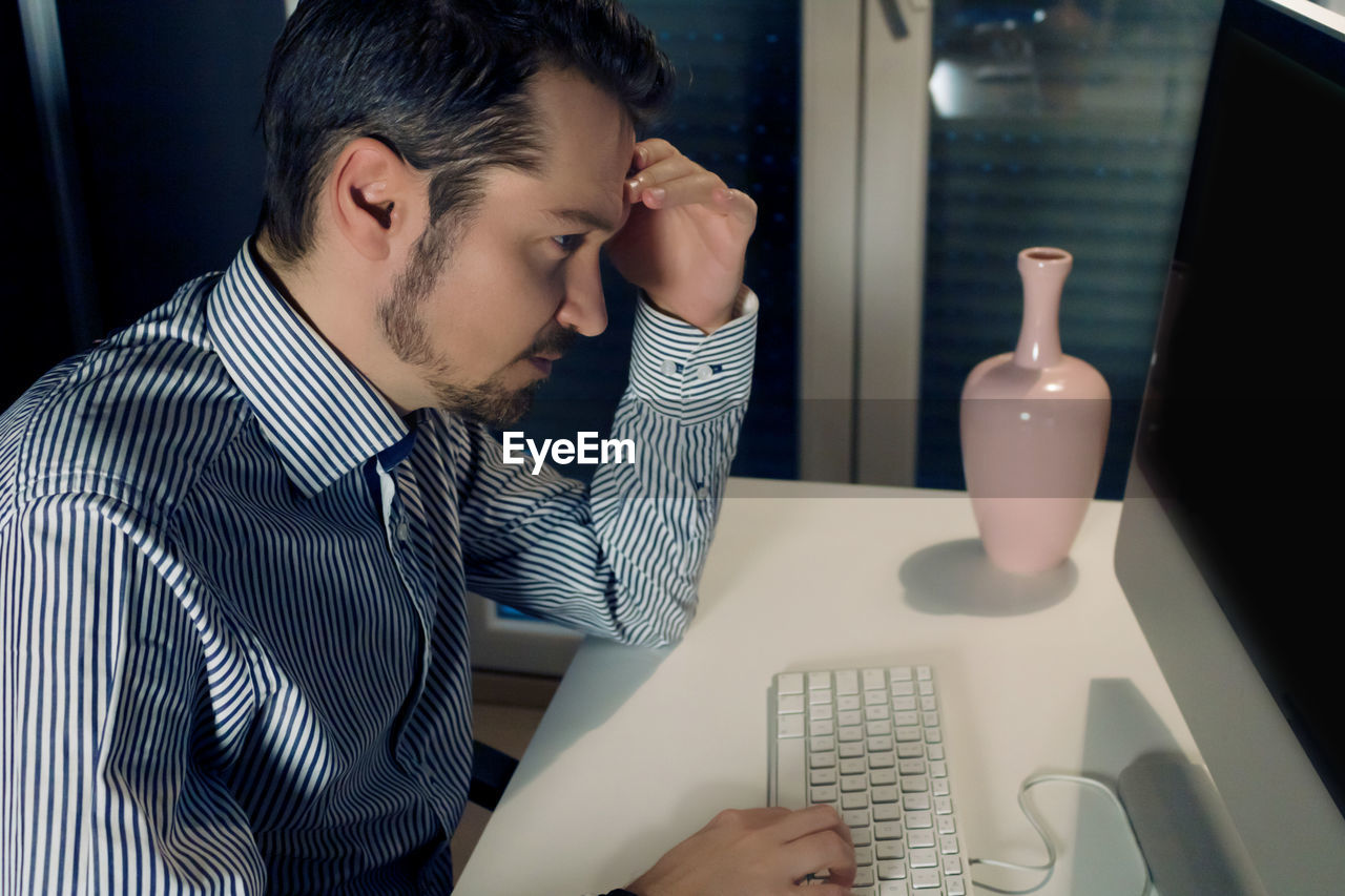 Pensive businessman reading problematic e-mail on a computer while working at home.