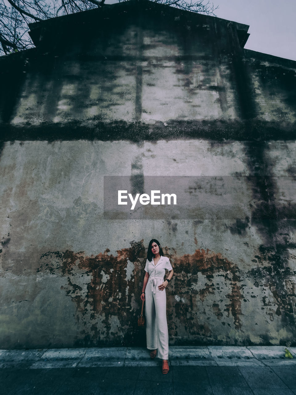 Full length portrait of woman standing against building