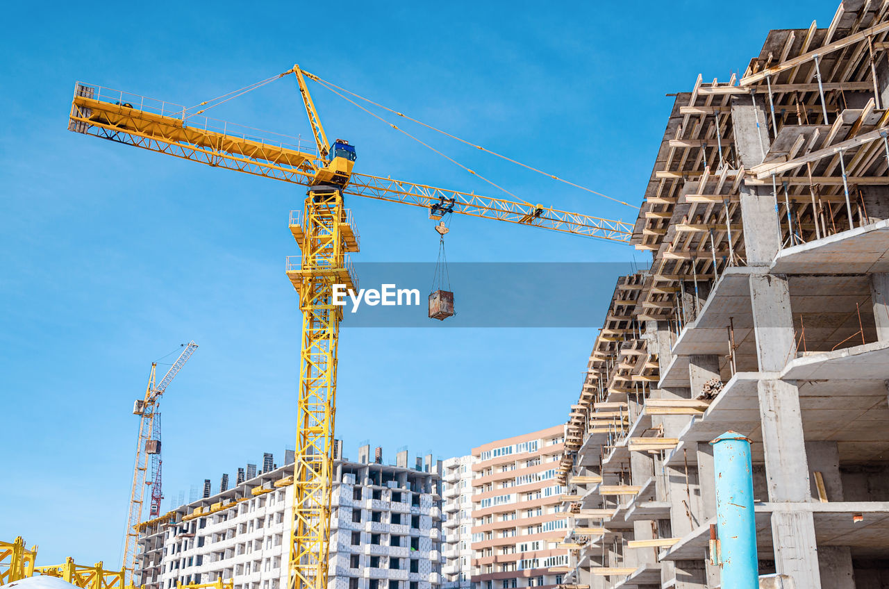 Construction of multi-storey building.yellow and blue cranes. cargo transfer.