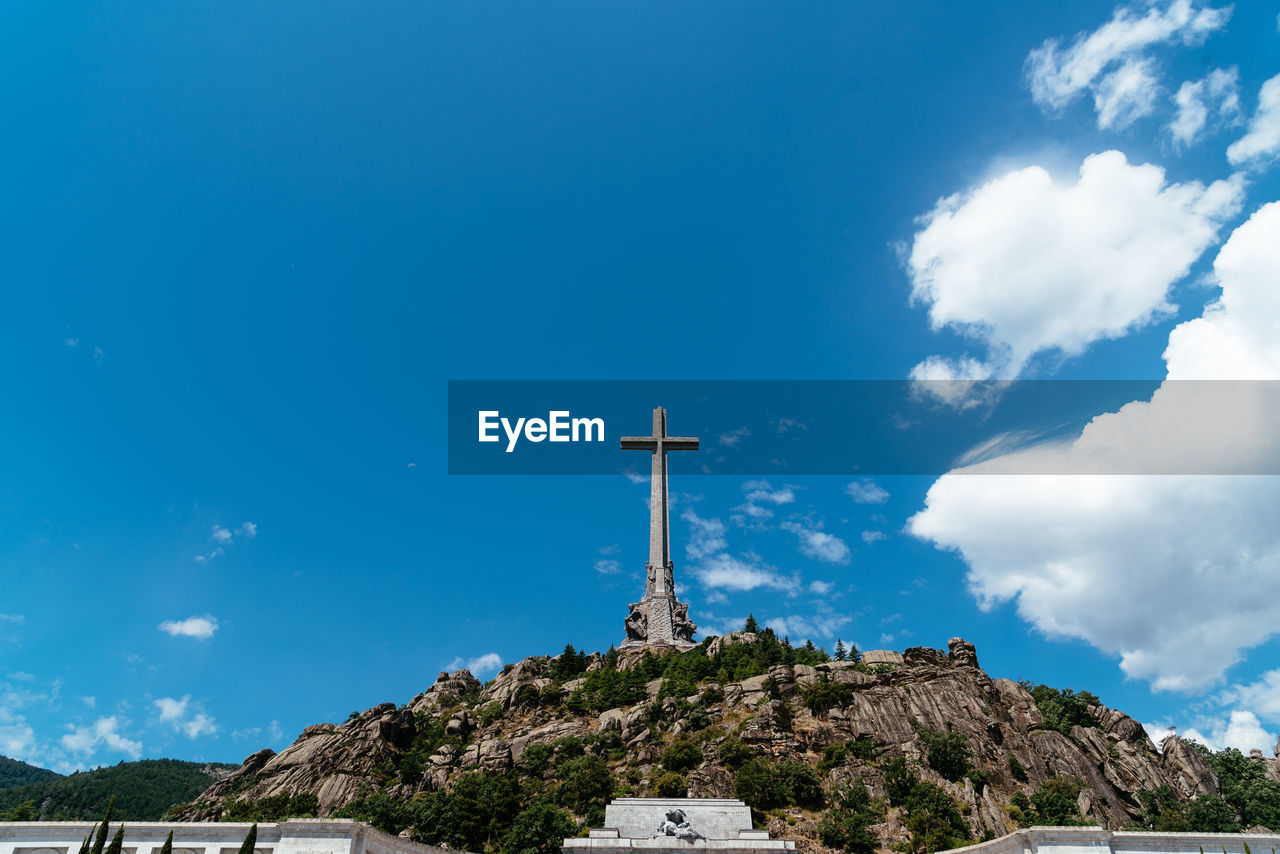 Low angle view of cross on mountain against sky