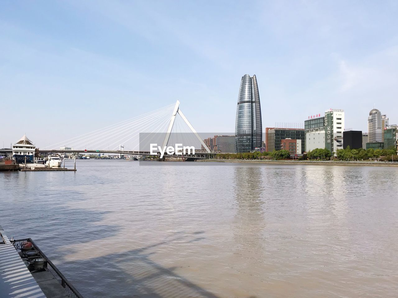 Bridge over river by city buildings against sky