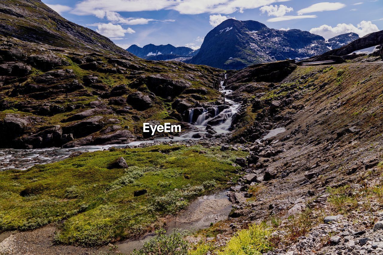 Scenic view of waterfall and mountains against sky